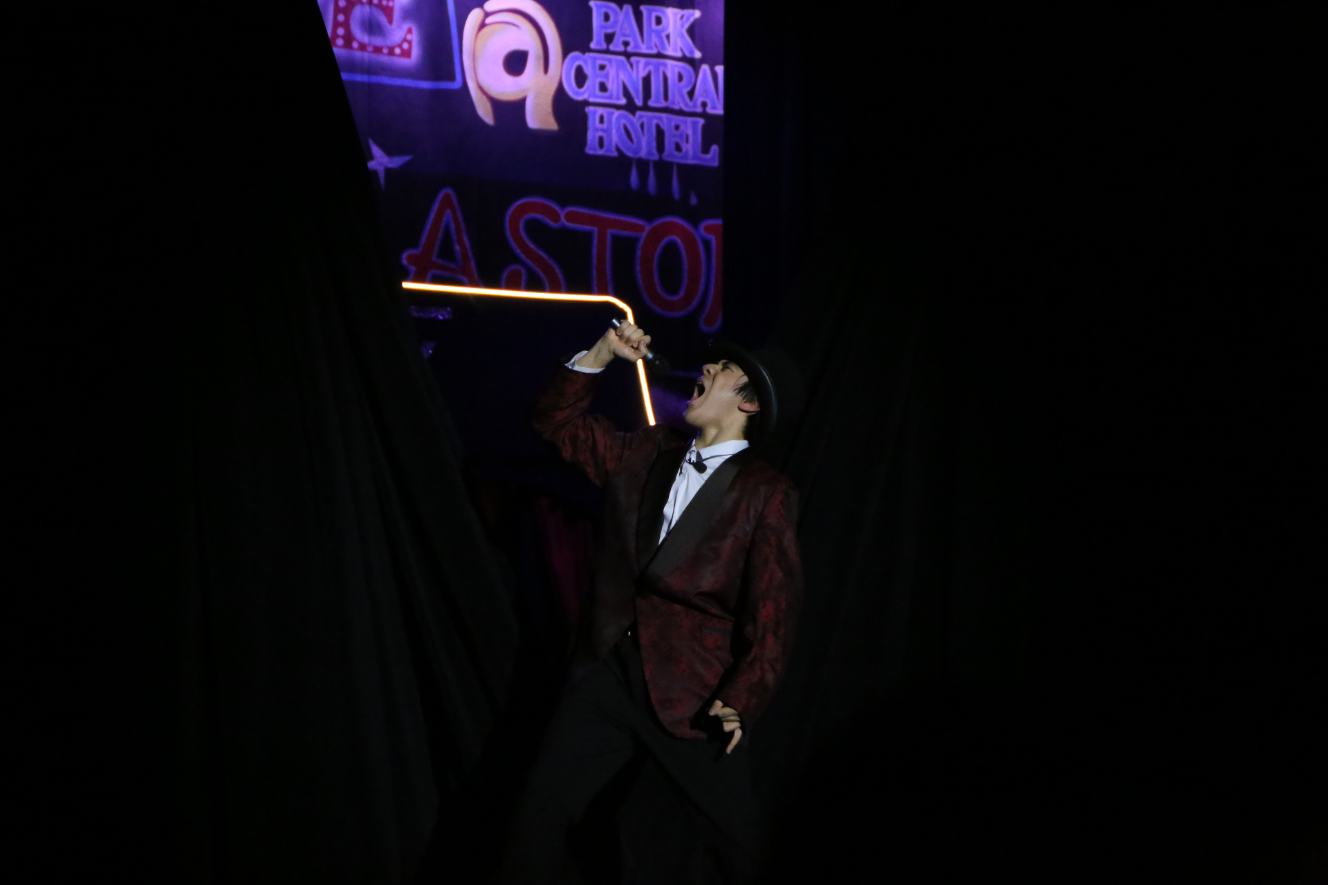 Belting into the mic under the Park Central Hotel sign