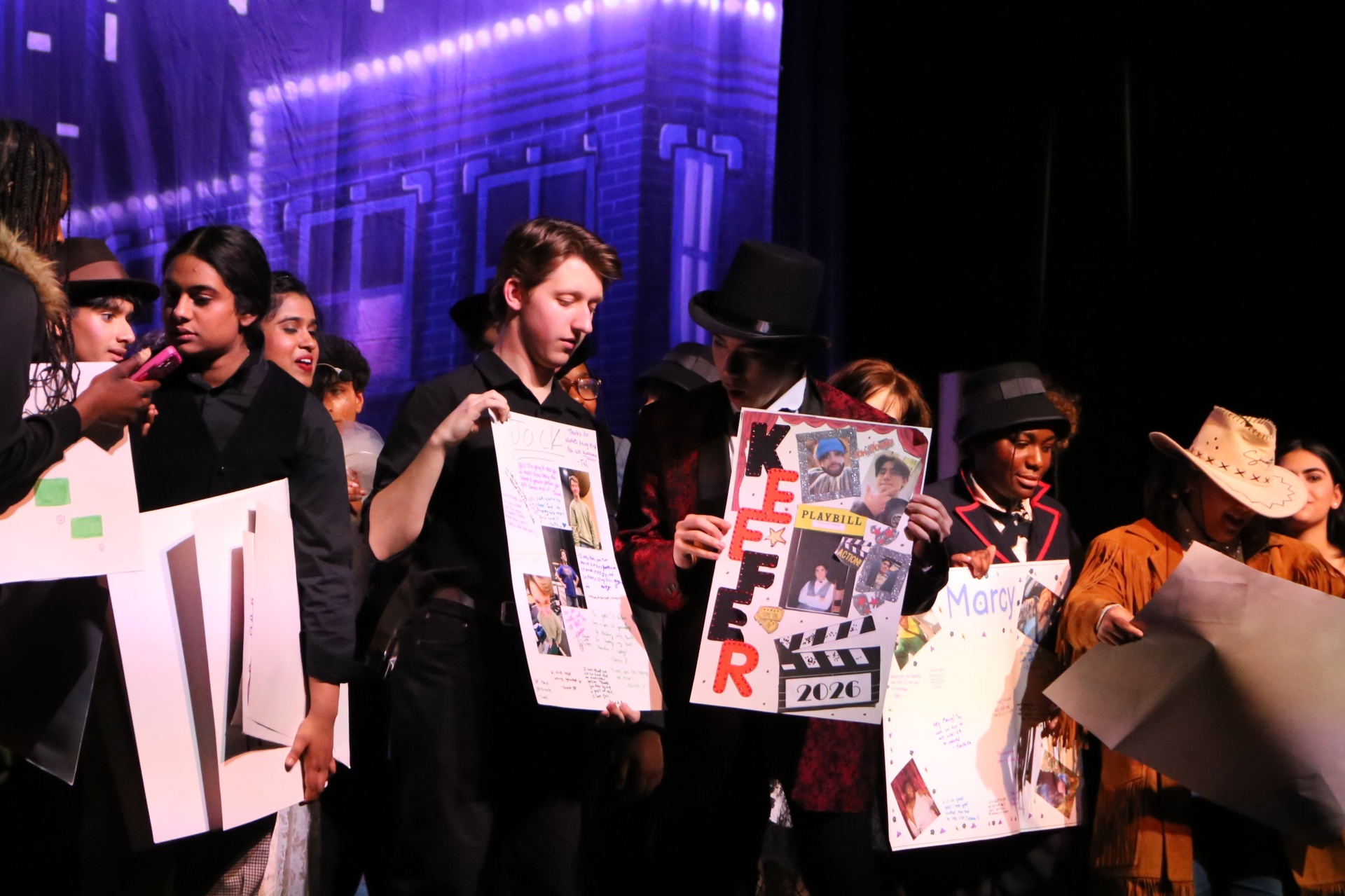 Cast on stage with senior night posters
